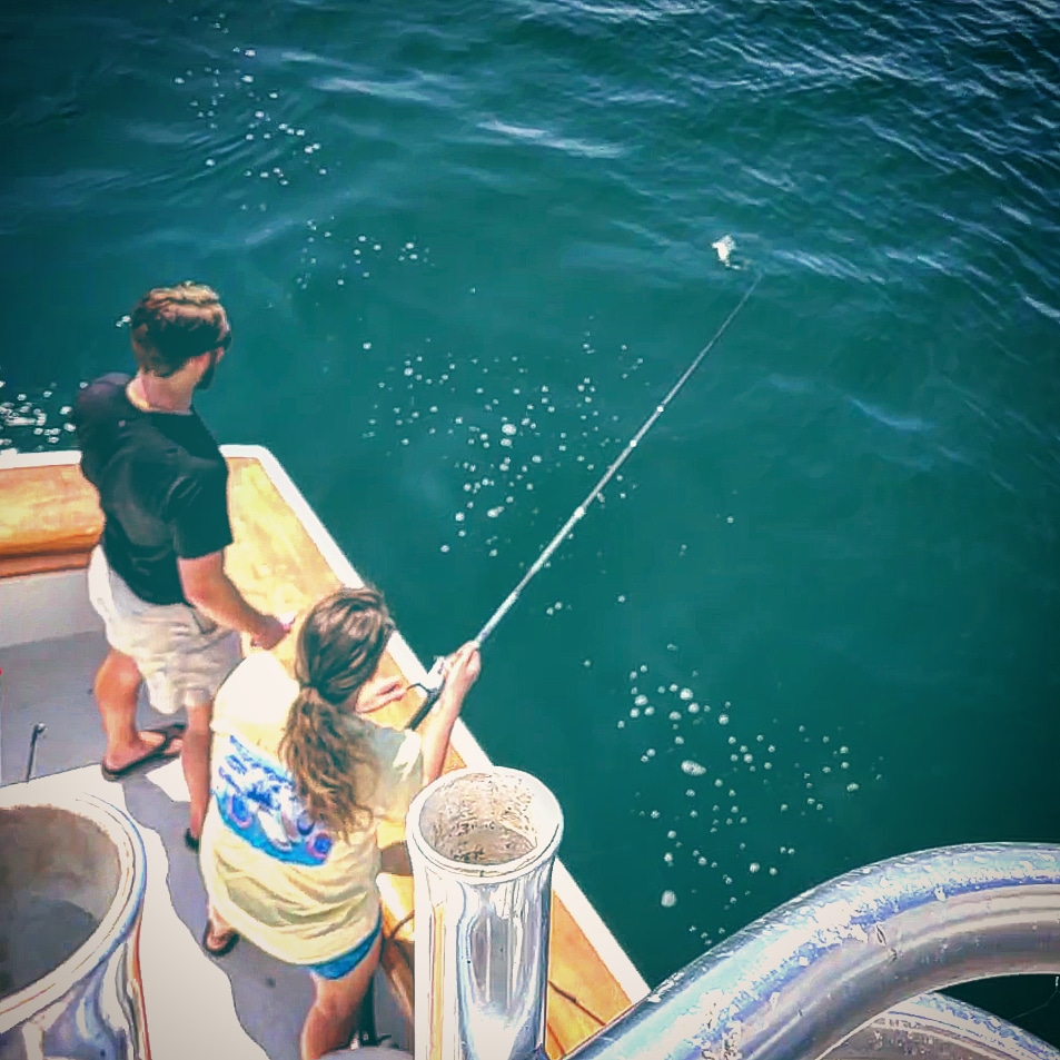 Lady angler reeling in a fish on a private deep sea fishing charter in Destin, Florida